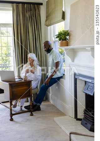 Couple enjoying coffee and conversation at home, planning wedding details together Couple enjoying coffee and conversation at home, planning wedding details together 135541623