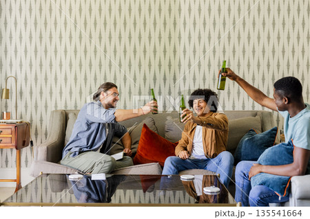 Friends celebrating with drinks on sofa, enjoying joyful moments together at home Friends celebrating with drinks on sofa, enjoying joyful moments together at home 135541664