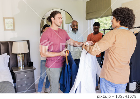 Groom and friends preparing suits for wedding day in cozy bedroom setting Groom and friends preparing suits for wedding day in cozy bedroom setting 135541679