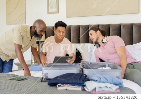 Friends packing suitcase together on bed, preparing for wedding day celebration Friends packing suitcase together on bed, preparing for wedding day celebration 135541820