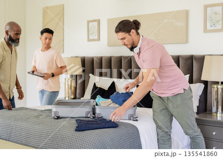 Friends packing suitcase in hotel room, preparing for wedding celebration together 135541860