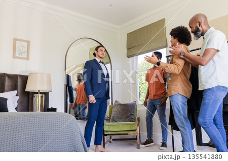 Groom in suit receiving applause from friends in bedroom before wedding ceremony 135541880