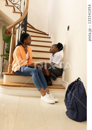 Mother and daughter sitting on stairs, sharing heartfelt conversation at home Mother and daughter sitting on stairs, sharing heartfelt conversation at home 135541954