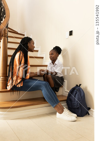 Mother and daughter sitting on stairs, having heartfelt conversation before school Mother and daughter sitting on stairs, having heartfelt conversation before school 135541992