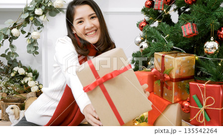 Asian woman holding christmas gift box under xmas tree with smiling face. Woman hands wrap present gift. Merry christmas happy new year concept. Woman surprise got present gift box on christmas eve Asian woman holding christmas gift box under xmas tree with smiling face. Woman hands wrap present gift. Merry christmas happy new year concept. Woman surprise got present gift box on christmas eve 135542264