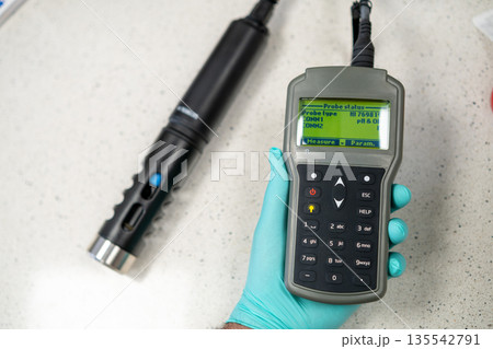 Probe status og pH meter or conductometer in woman hand in gloves. 135542791