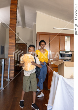 Mother and son unpacking boxes at home, smiling and enjoying new space Mother and son unpacking boxes at home, smiling and enjoying new space 135542927