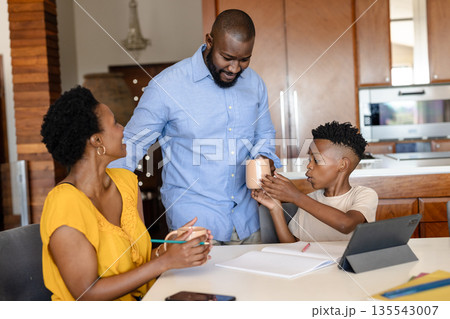 Family enjoying quality time at home, sharing drinks and using tablet together Family enjoying quality time at home, sharing drinks and using tablet together 135543007