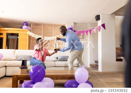 Exchanging gifts, joyful couple celebrating at home with festive decorations around 135543032