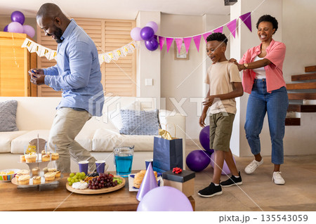 Celebrating birthday at home, family dancing with festive decorations together Celebrating birthday at home, family dancing with festive decorations together 135543059