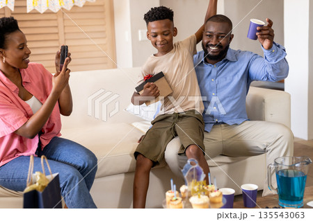 Celebrating at home, joyful family enjoying birthday party with gifts and cupcakes 135543063