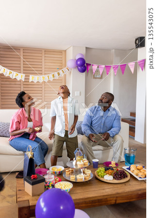 Family enjoying birthday celebration at home with snacks and colorful decorations Family enjoying birthday celebration at home with snacks and colorful decorations 135543075