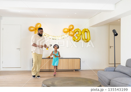 Father and child celebrating birthday with balloons and decorations at home Father and child celebrating birthday with balloons and decorations at home 135543199