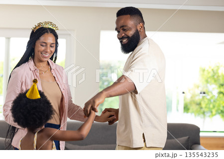 Family celebrating birthday at home, smiling and dancing together in living room Family celebrating birthday at home, smiling and dancing together in living room 135543235