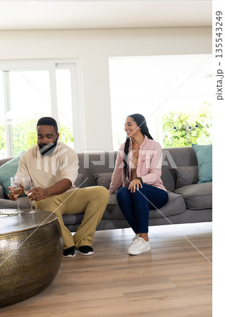 Couple relaxing on sofa, enjoying drinks and sharing joyful conversation at home Couple relaxing on sofa, enjoying drinks and sharing joyful conversation at home 135543249