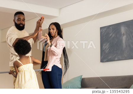 Dancing playfully at home, African American family smiling and laughing together 135543295