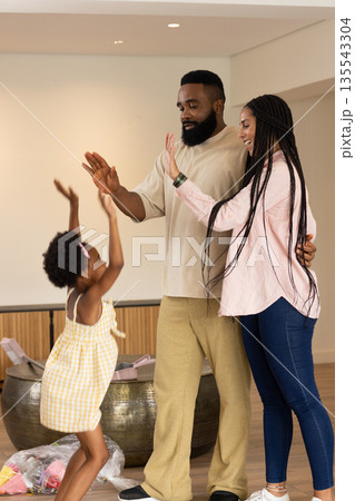 Family enjoying playful high-five moment at home, sharing joyful laughter together Family enjoying playful high-five moment at home, sharing joyful laughter together 135543304