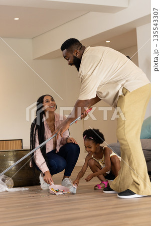 African American family cleaning living room together, smiling and enjoying teamwork African American family cleaning living room together, smiling and enjoying teamwork 135543307