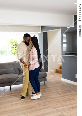 African American couple dancing together in living room, sharing joyful moment 135543323