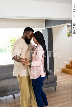 Couple dancing together at home, enjoying tender moment in living room 135543327