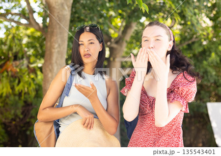 Blowing kisses and posing, two young women enjoy sunny day outdoors Blowing kisses and posing, two young women enjoy sunny day outdoors 135543401
