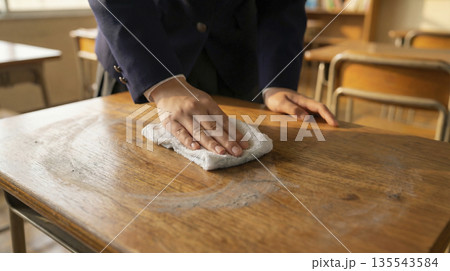 教室の木製の机を雑巾掛けする女子高生の手元 拭き掃除のクローズアップ 135543584