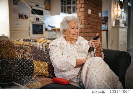 Elderly woman watching television alone at home. 135544064
