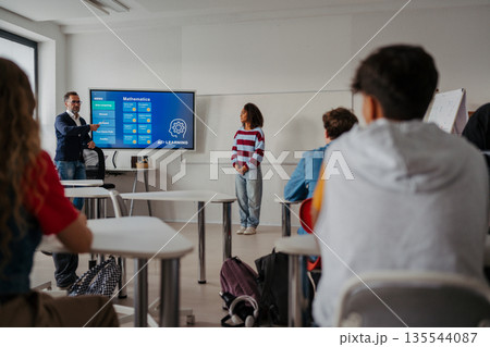 Teen girl presenting AI learning project in classroom. Teen girl presenting AI learning project in classroom. 135544087