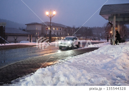 Car driving on a snowy street at dusk in winter 135544328