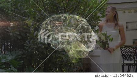Hovering brain hologram floating above patio chairs, with woman in sleeveless dress holding bouquet 135544628
