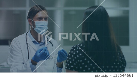 Male physician wearing mask and gloves administering injection at clinic, featuring syringe 135544661