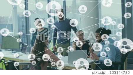 Five professionals in business casual attire analyzing network icons on laptop in meeting room 135544780