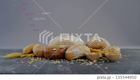 Showing artisanal breads, buns, oats, wheat stalks on dark studio tabletop, with code text overlay 135544950