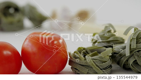 Arranging fresh red tomatoes and green pasta nests at kitchen prep area, with digital data network 135544979