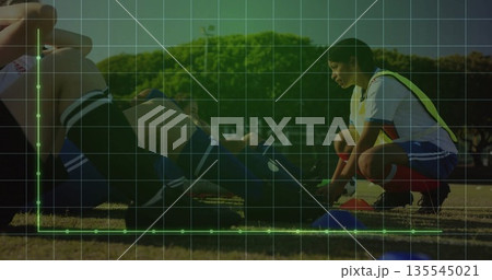 Soccer player wearing yellow bib tying cleats on grass field, with blue training cones, copy space Soccer player wearing yellow bib tying cleats on grass field, with blue training cones, copy space 135545021