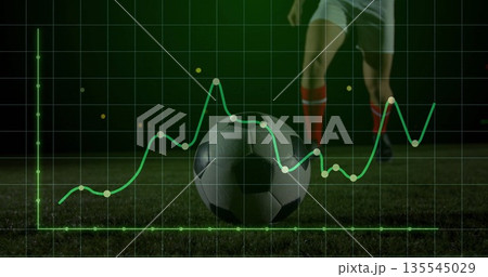 Resting soccer ball showing grid and line graph metrics on floodlit pitch, with player legs nearby 135545029