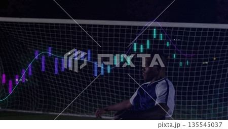 Posing soccer player wearing gear on pitch before goal net with neon candlestick chart, copy space 135545037