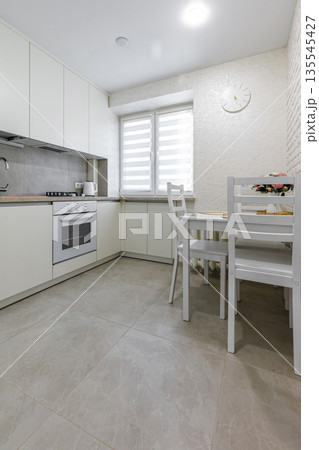 Bright modern kitchen and dining area with white furniture 135545427