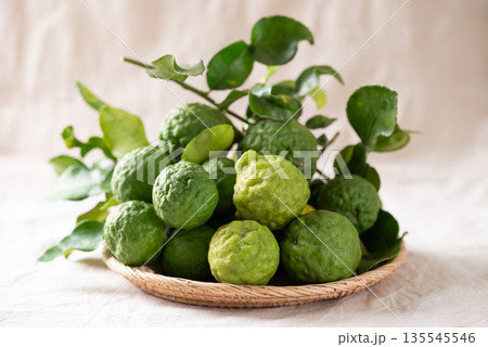 Kaffir lime fruit with leaf in basket on white fabric background, Thai food ingredient 135545546