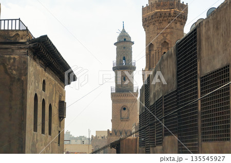 Historic Qalawun Complex in Cairo, featuring intricate architecture, tall minarets, and domes under a blue sky with clouds. A significant cultural landmark on Al-Muizz Street. 135545927
