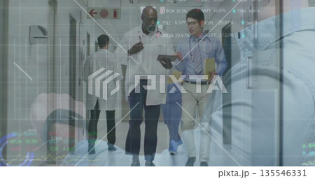 Walking medical team discussing data in hospital corridor, with tablet, folder and overlay charts Walking medical team discussing data in hospital corridor, with tablet, folder and overlay charts 135546331