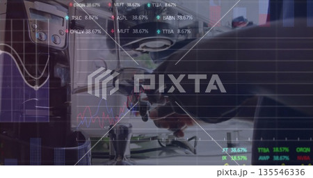 Barista in bib apron locking portafilter into machine at cafe counter, with tamper and stock charts Barista in bib apron locking portafilter into machine at cafe counter, with tamper and stock charts 135546336