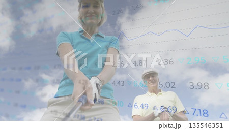 Swinging mature female golfer gripping golf club on driving range, with data overlay and golf glove 135546351
