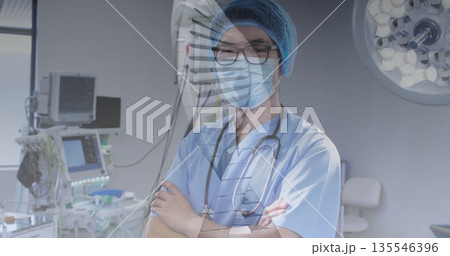 Standing mature Chinese surgeon crossing arms in hospital operating room, with medical monitors Standing mature Chinese surgeon crossing arms in hospital operating room, with medical monitors 135546396