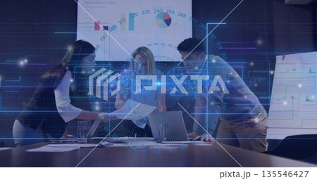 Analyzing professionals reviewing printed charts around meeting table with laptops, whiteboard 135546427