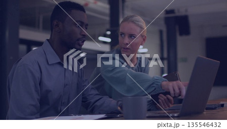 Pointing coworker with tablet guiding colleague at office, with laptop papers smartphone coffee mug 135546432