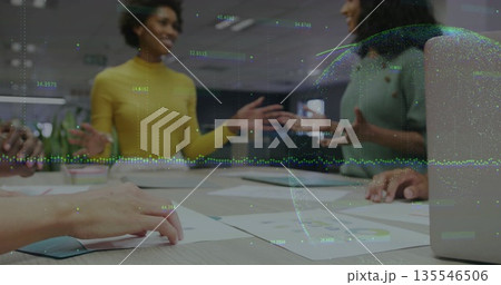 Collaborating team of five analyzing reports and laptop around conference table, with data graphics 135546506