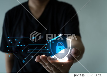 Hand holding glowing digital shield with lock and data lines, symbolizing cybersecurity 135547935