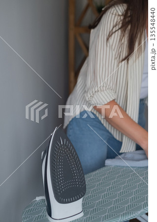 Steam treatment of clothes to kill bacteria woman in casual clothes ironing garments caring for family health 135548440