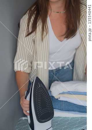Home clothes sterilization with woman carefully steaming garments maintaining cleanliness and order in the wardrobe 135548441